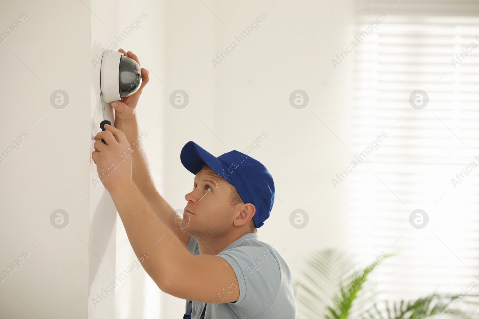 Photo of Technician installing CCTV camera on wall indoors