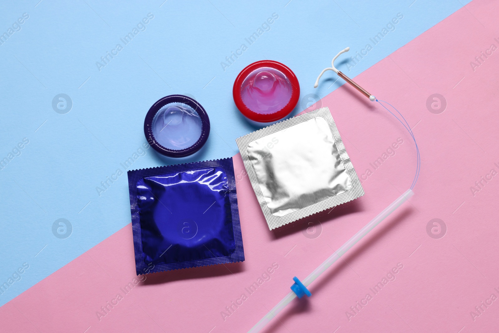 Photo of Condoms and intrauterine device on color background, flat lay. Choosing method of contraception