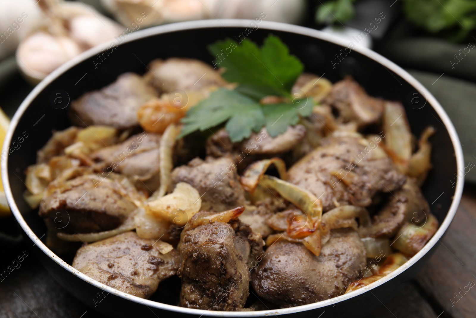 Photo of Tasty fried chicken liver with parsley and onion on table, closeup