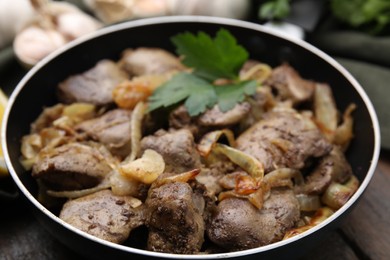 Tasty fried chicken liver with parsley and onion on table, closeup