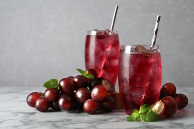 Photo of Delicious grape soda water with mint and berries on white marble table. Refreshing drink