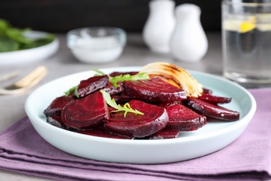 Photo of Roasted beetroot slices with onion and arugula on table, closeup