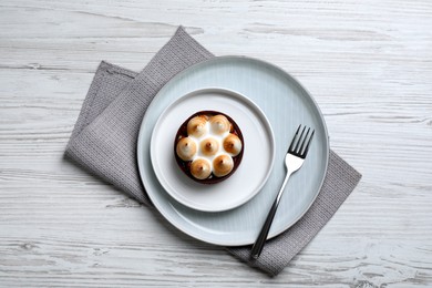 Photo of Delicious salted caramel chocolate tart with meringue served on white wooden table, top view