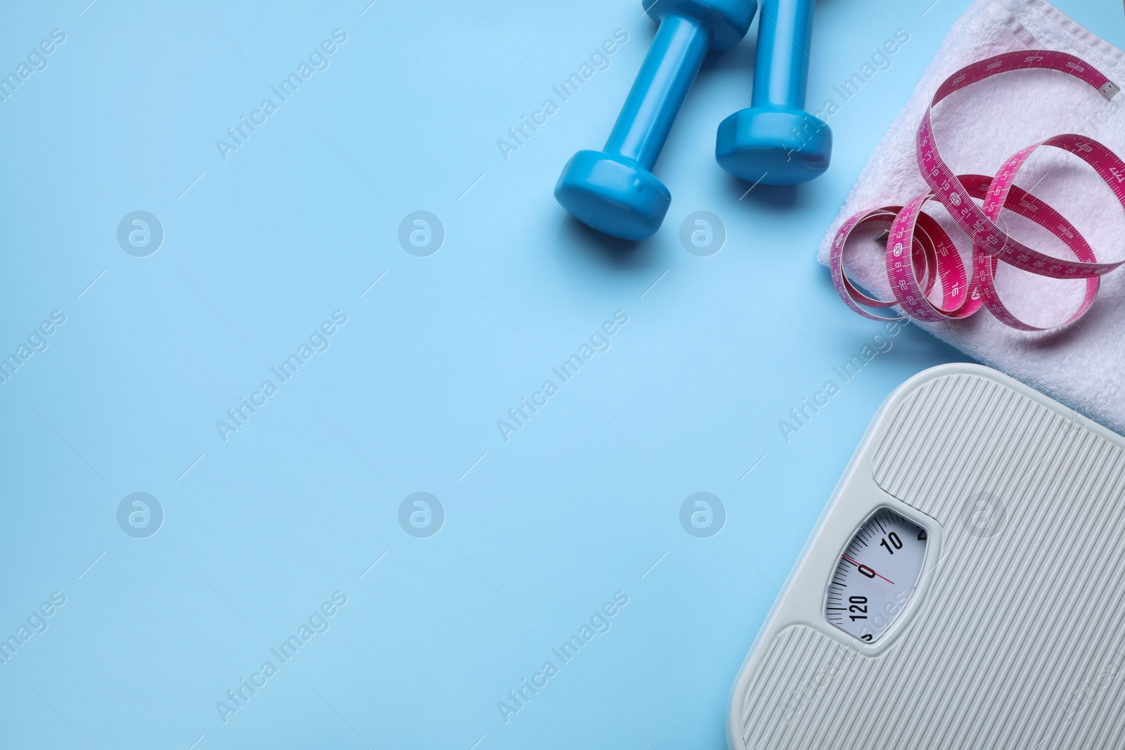 Photo of Scales, measuring tape, dumbbells and towel on light blue background, flat lay. Space for text