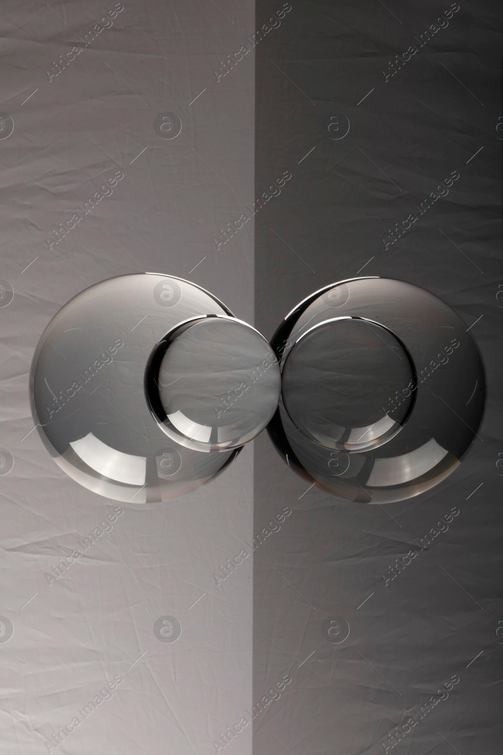 Photo of Transparent glass balls on mirror surface against light background