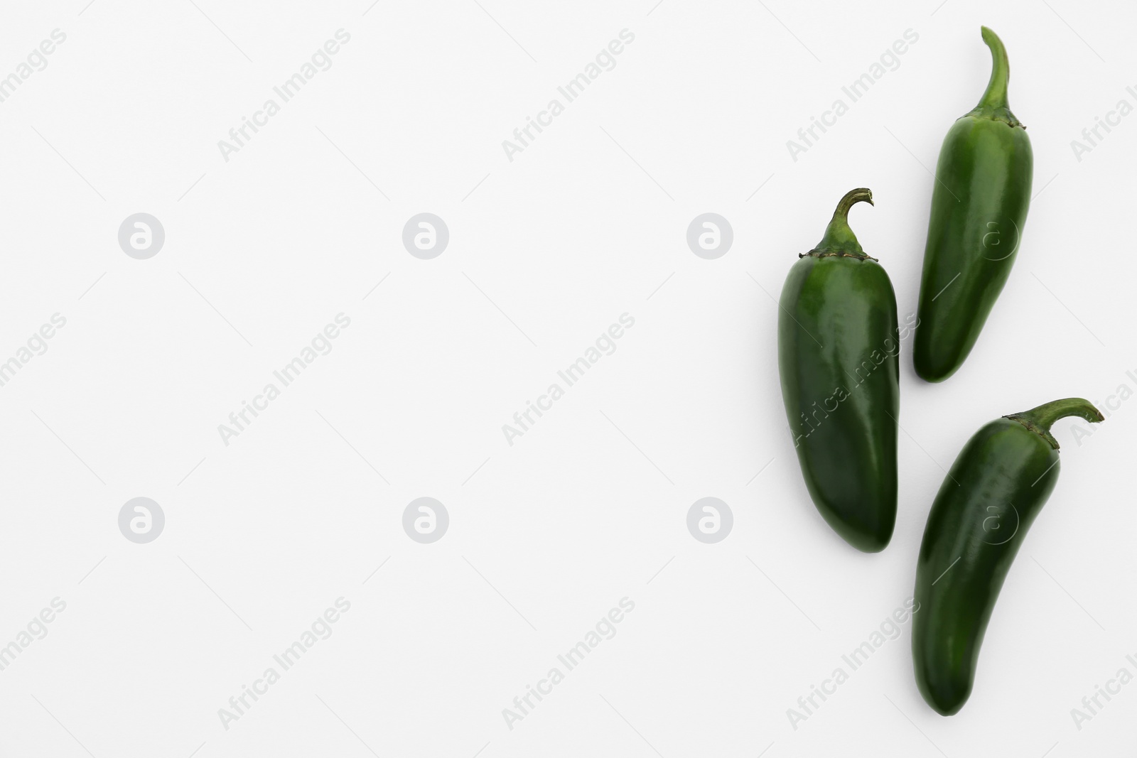 Photo of Green hot chili peppers on white background, flat lay. Space for text