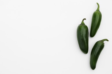 Photo of Green hot chili peppers on white background, flat lay. Space for text
