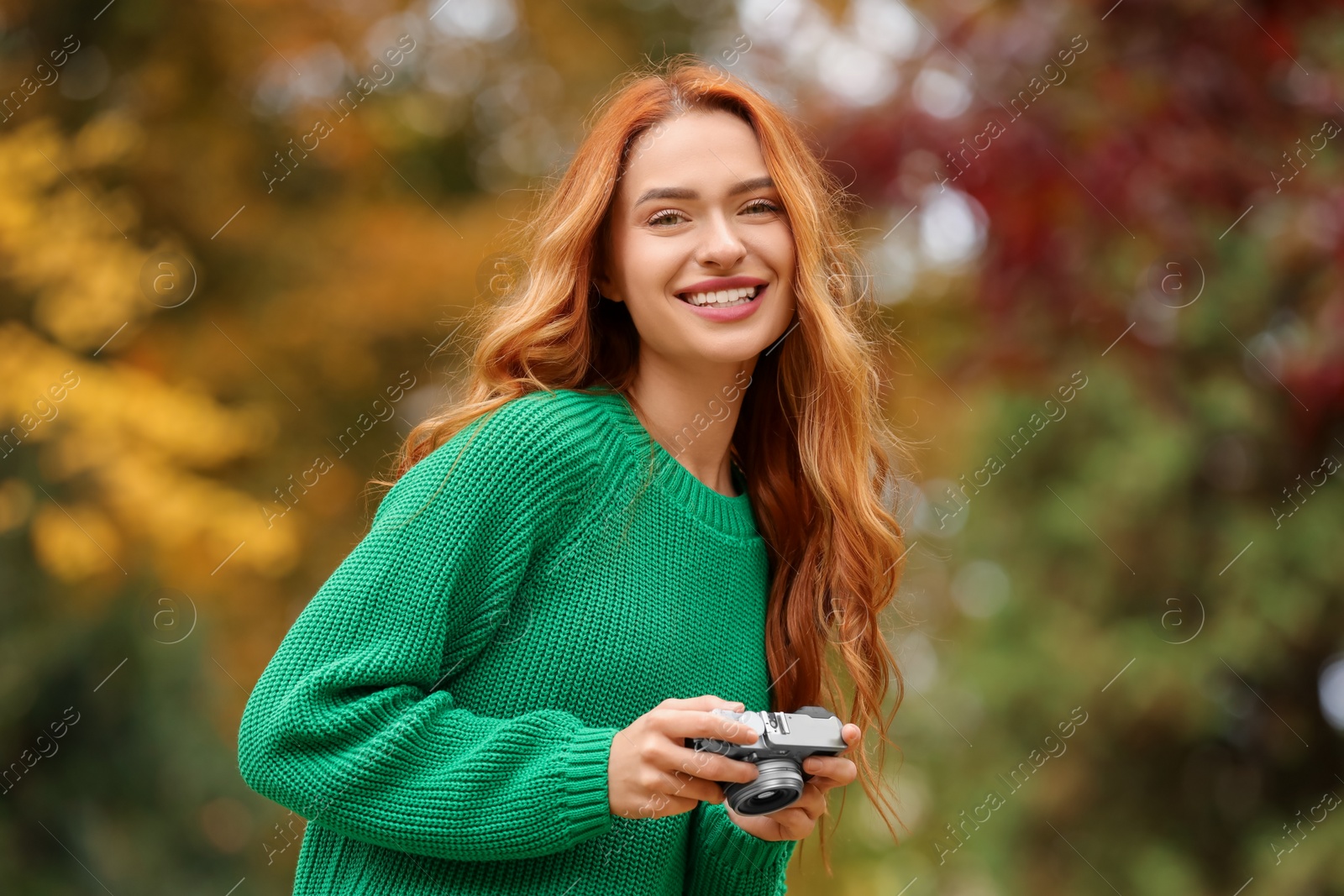 Photo of Smiling woman with camera in autumn park