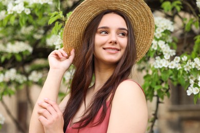 Photo of Beautiful woman in straw hat near blossoming tree on spring day