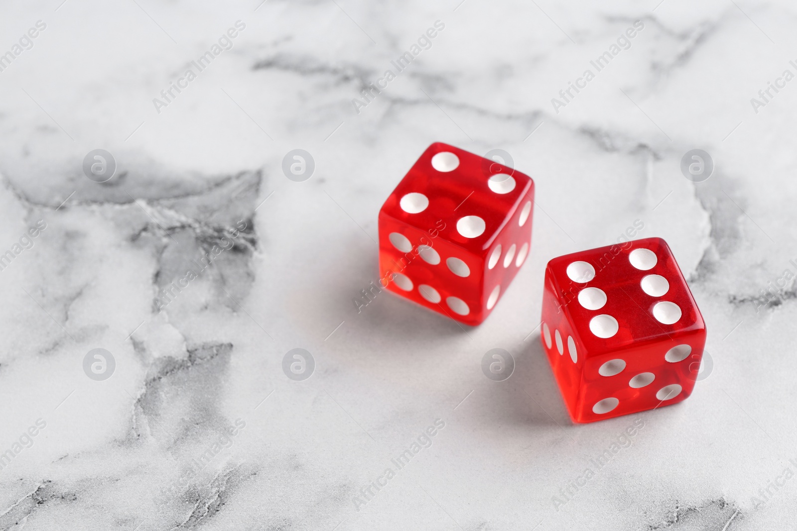 Photo of Two red game dices on white marble table. Space for text