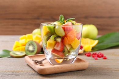Delicious fresh fruit salad in dish on wooden table
