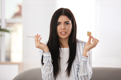 Photo of Emotional young woman with nicotine patch and cigarette at home