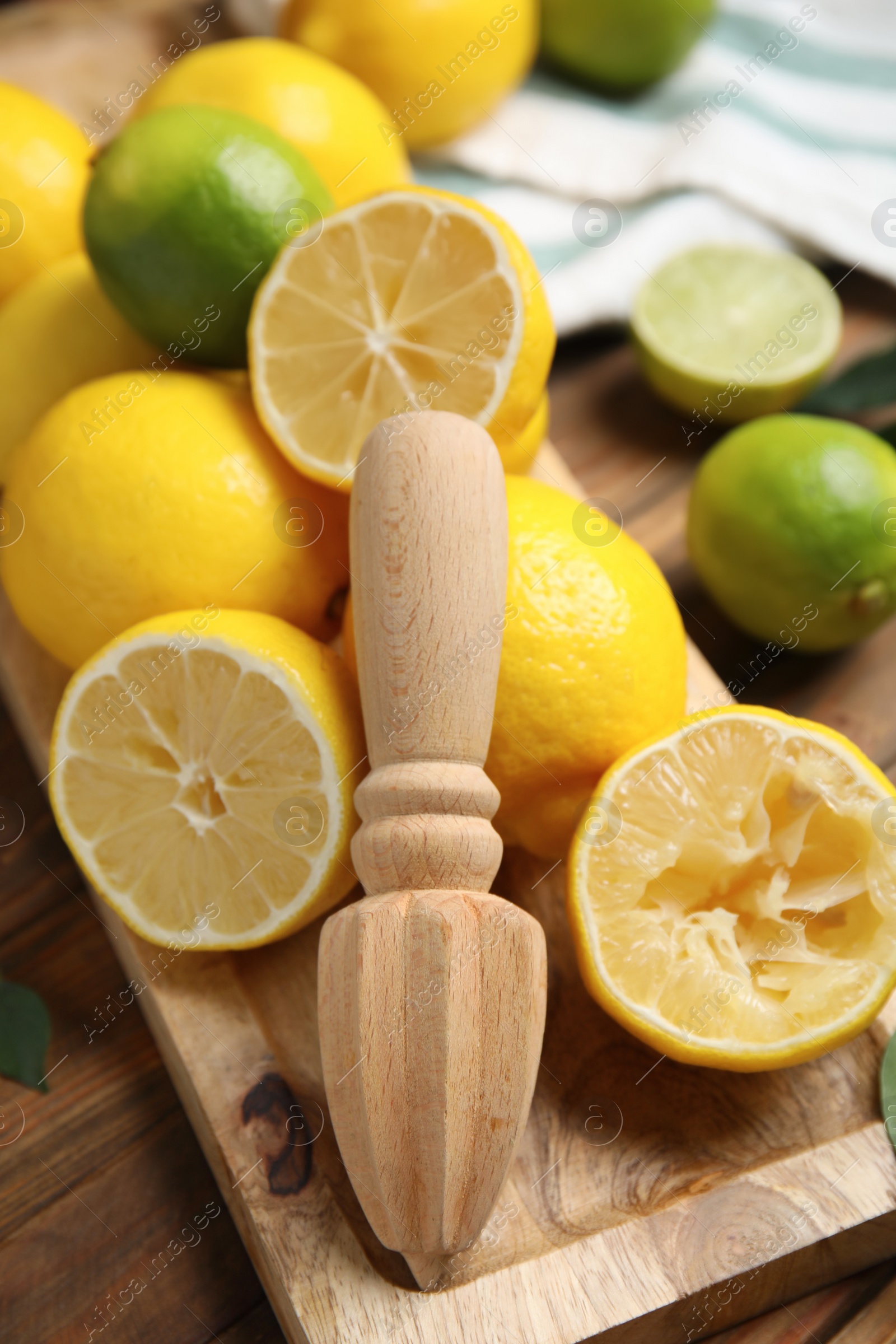 Photo of Squeezer with lemons on wooden table, closeup