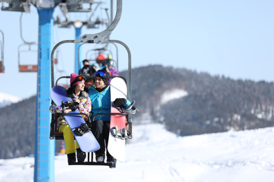 People using chairlift at mountain ski resort, space for text. Winter vacation