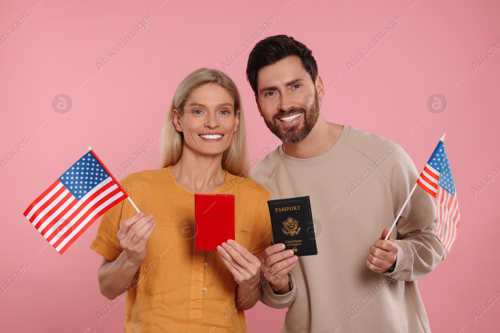 Photo of Immigration. Happy couple with passports and American flags on pink background