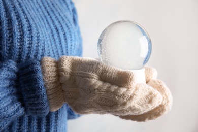 Photo of Woman holding empty snow globe on light background, closeup