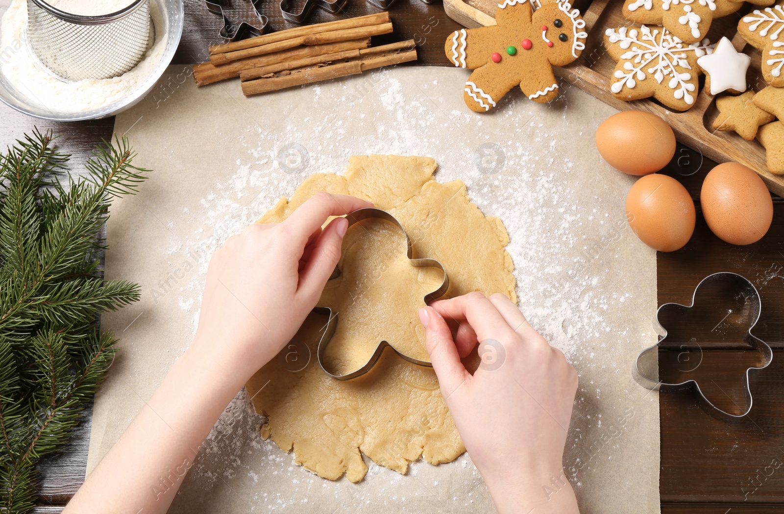 Photo of Woman making Christmas cookies with cutters at wooden table, top view