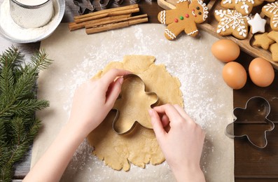 Photo of Woman making Christmas cookies with cutters at wooden table, top view