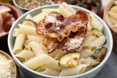 Tasty pasta with bacon and cheese on grey table, closeup