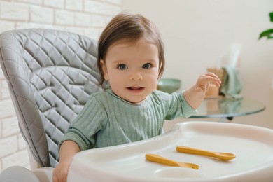 Photo of Cute little baby sitting in high chair indoors