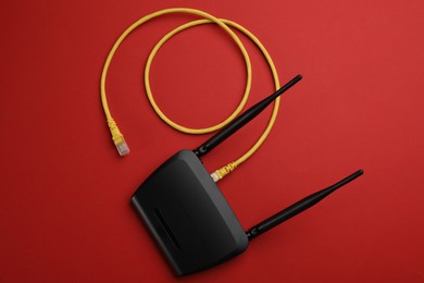 Modern Wi-Fi router on red background, top view