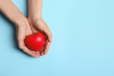 Photo of Woman holding heart on blue background, top view with space for text. Donation concept