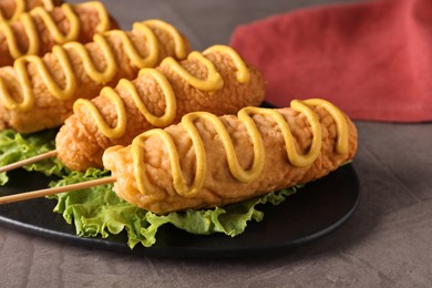 Photo of Delicious corn dogs with mustard served on grey table, closeup