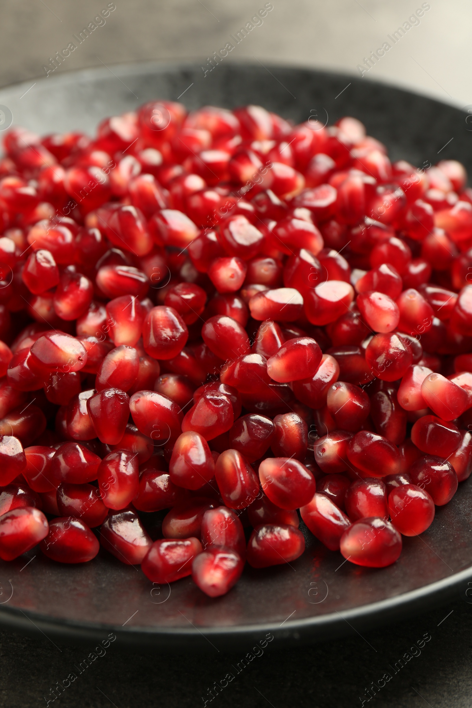 Photo of Ripe juicy pomegranate grains on grey table, closeup