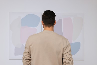 Photo of Man at exhibition in art gallery, back view