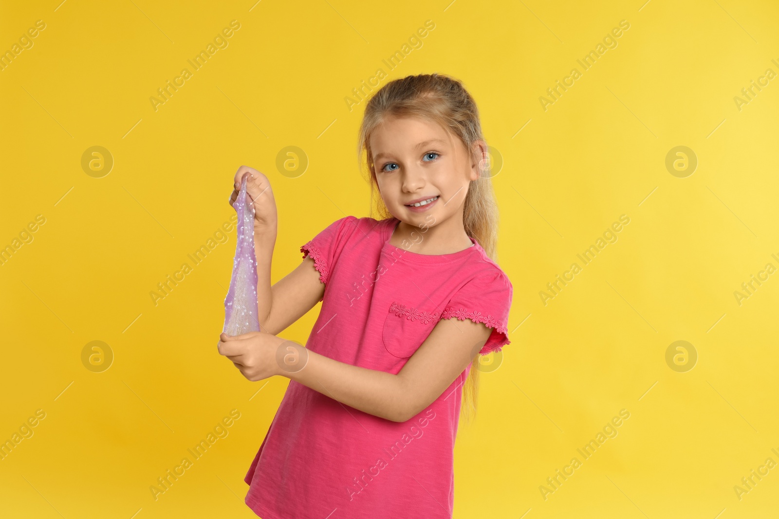 Photo of Little girl with slime on yellow background