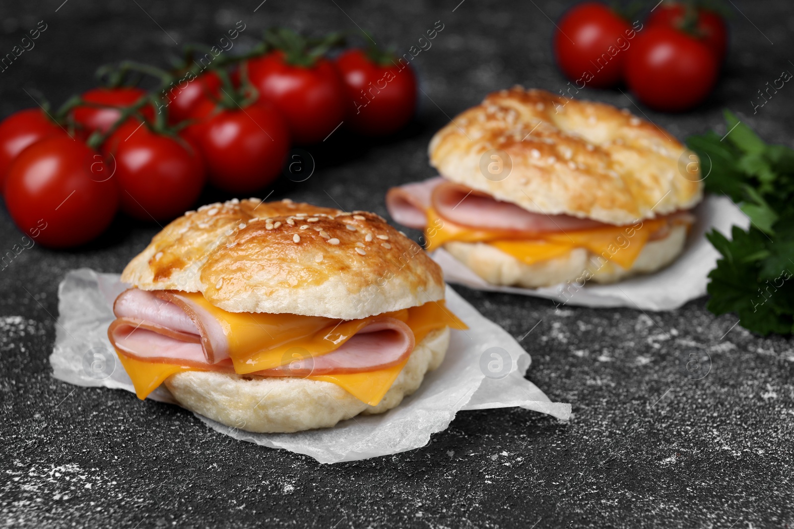 Delicious bagels with ham and cheese on dark grey textured table, space for text Photo of Delicious bagels with ham and cheese on dark grey textured table, space for text