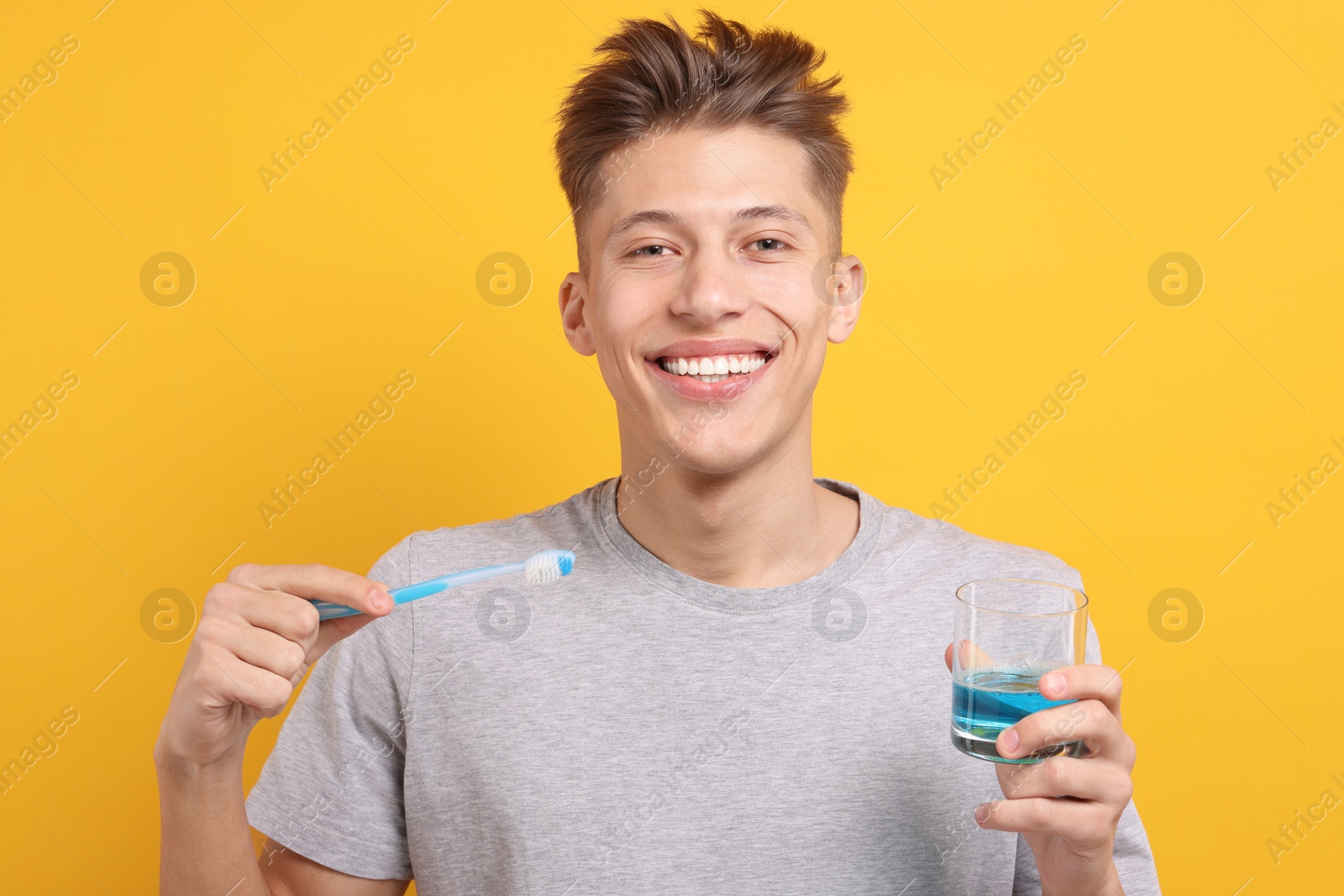 Photo of Young man with mouthwash and toothbrush on yellow background