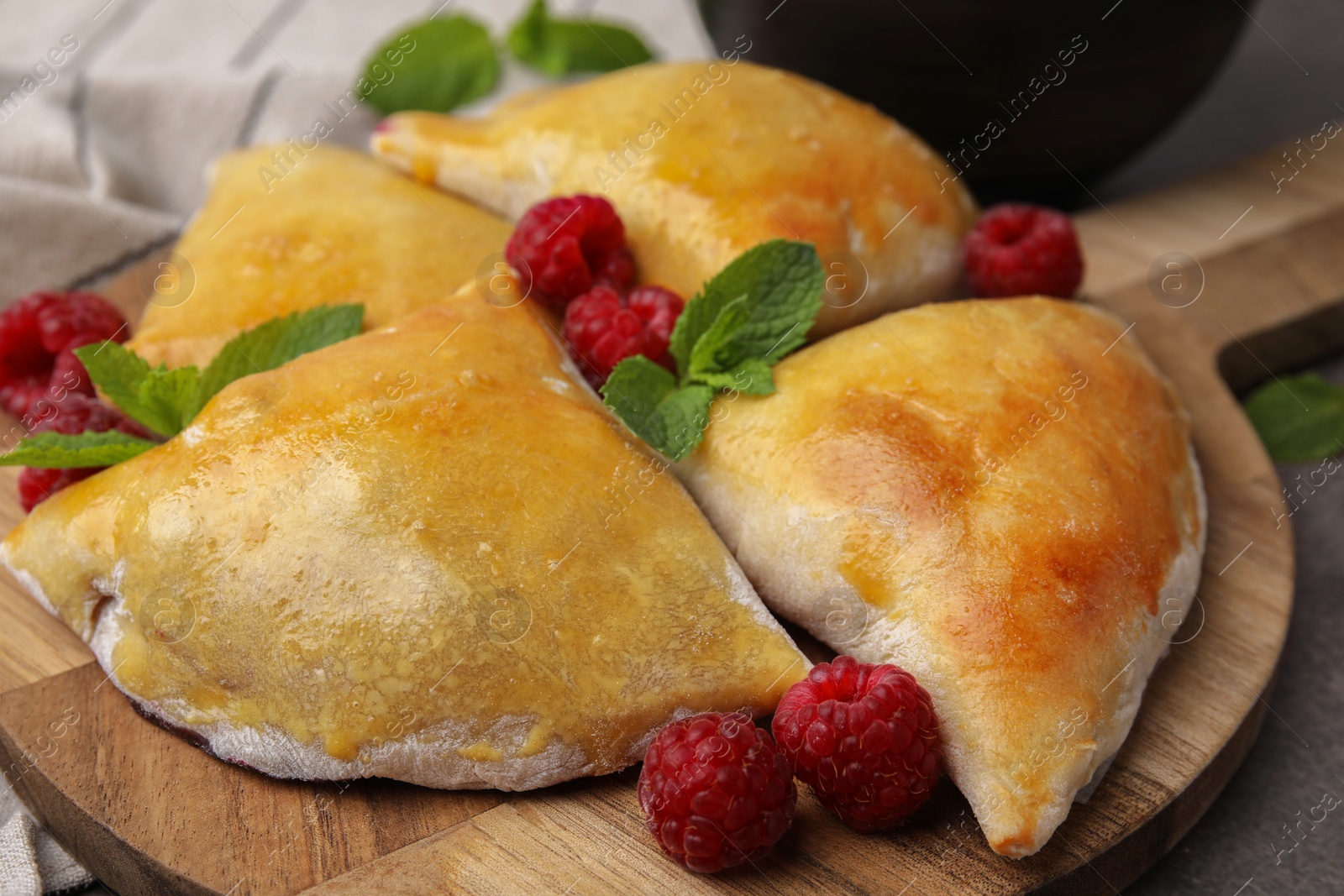 Photo of Delicious samosas with raspberries on grey table, closeup