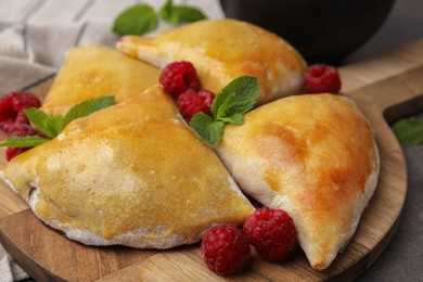Photo of Delicious samosas with raspberries on grey table, closeup