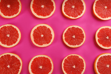 Photo of Flat lay composition with tasty ripe grapefruit slices on magenta background