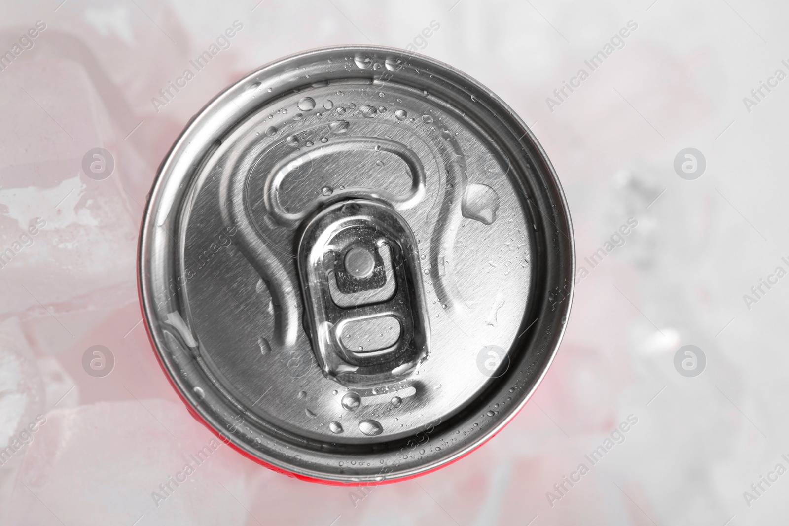 Photo of Energy drink in wet can and ice cubes on light background, top view