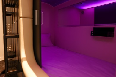 Capsule with bed and purple light in modern pod hostel