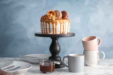 Photo of Dessert stand with delicious caramel cake on table against color background