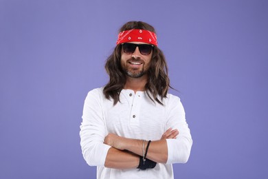 Photo of Stylish hippie man in sunglasses on violet background