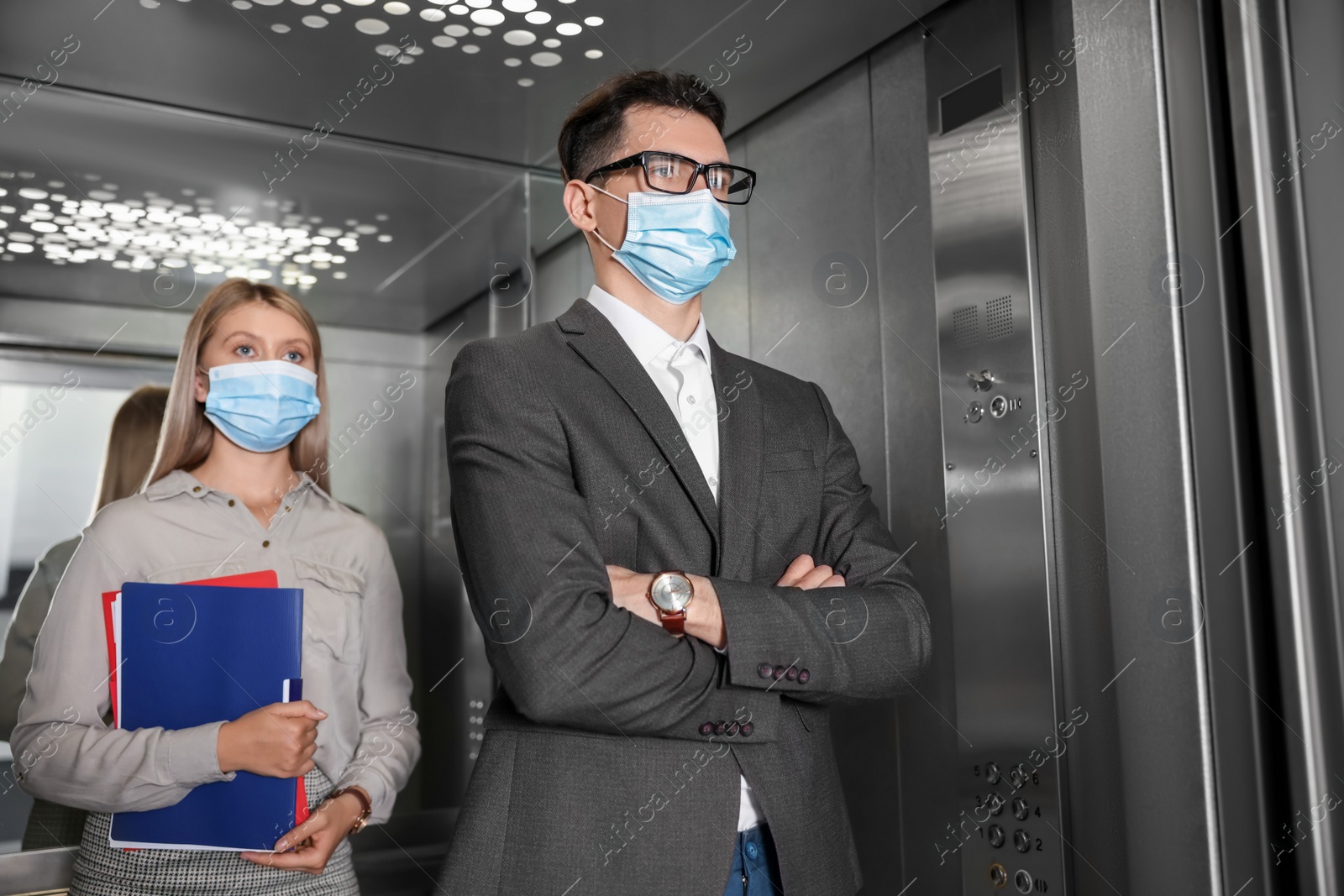 Photo of Coworkers with face masks in elevator. Protective measure
