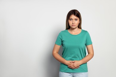 Photo of Young woman suffering from menstrual pain on grey background. Space for text
