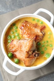 Tasty cooked rabbit meat with sauce and peas on table, top view