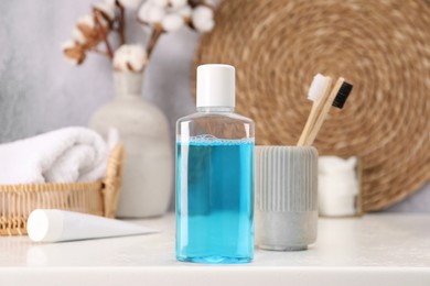 Bottle of mouthwash and toothbrushes on white table in bathroom