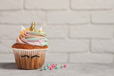 Cute sweet unicorn cupcake on light grey table, space for text