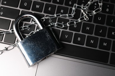 Photo of Cyber security. Padlock with chain on laptop, top view