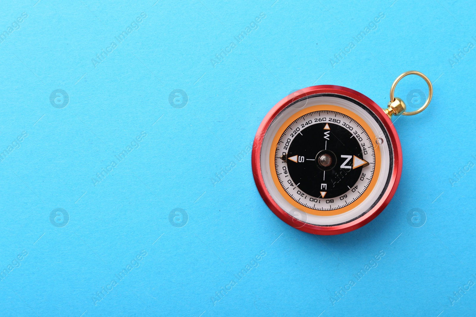 Photo of Compass on light blue background, top view. Space for text