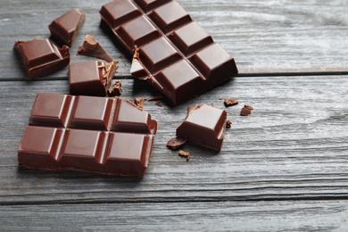 Pieces of tasty chocolate on wooden background. Space for text