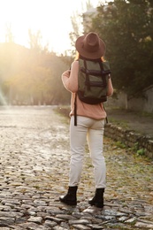 Traveler with backpack on city street, back view