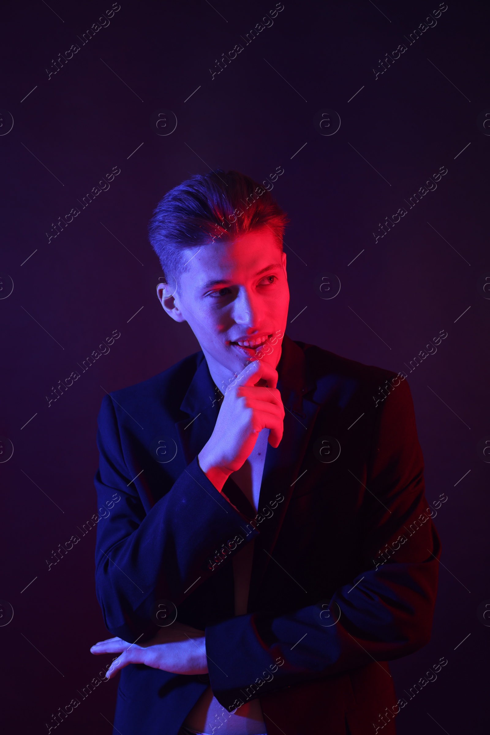 Photo of Young man on dark background in neon lights