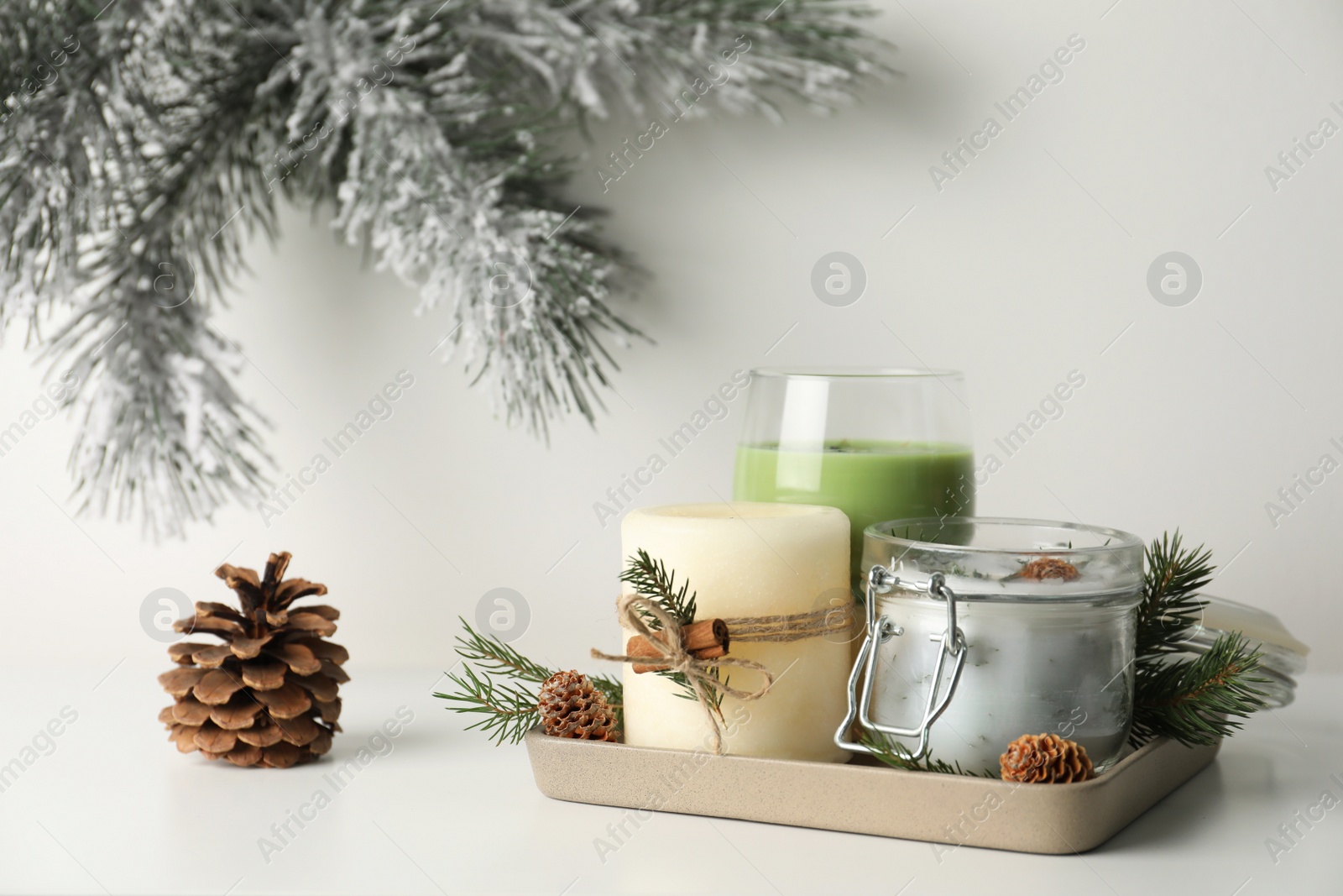 Photo of Composition with scented conifer candles and Christmas decor on white table